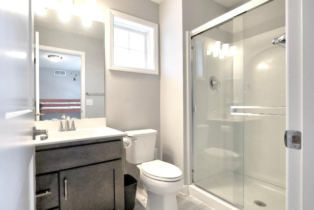 bathroom featuring vanity, a shower with shower door, toilet, and plenty of natural light