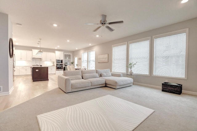 living room with light colored carpet, ceiling fan, and sink