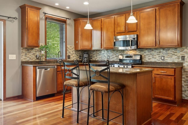 kitchen featuring hanging light fixtures, light hardwood / wood-style floors, a center island, and appliances with stainless steel finishes