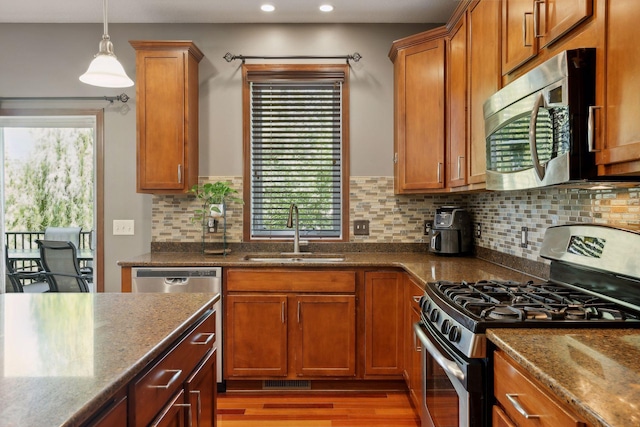 kitchen with sink, stainless steel appliances, tasteful backsplash, wood-type flooring, and stone countertops