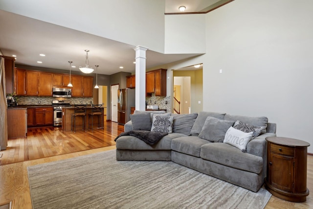 living room featuring decorative columns, light hardwood / wood-style floors, and a high ceiling