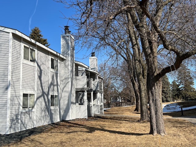 view of side of home with a balcony, a chimney, and fence