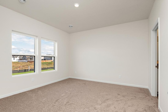 empty room featuring baseboards and light colored carpet