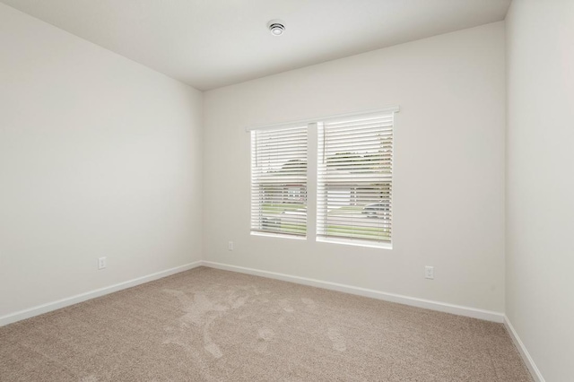 unfurnished room with light carpet and baseboards