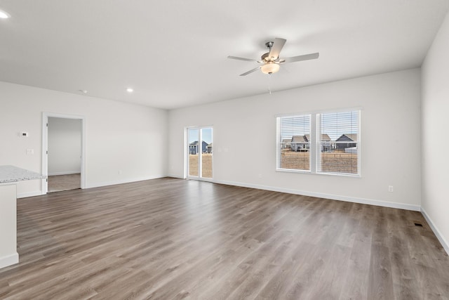 empty room with recessed lighting, ceiling fan, baseboards, and wood finished floors