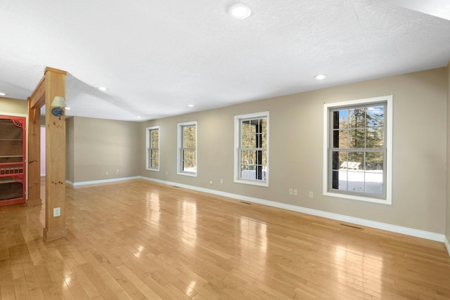 unfurnished living room with baseboards, a healthy amount of sunlight, and light wood-style floors