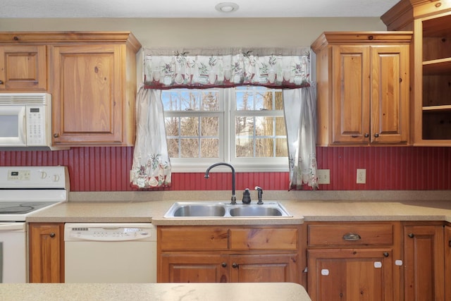 kitchen featuring light countertops, white appliances, and a sink