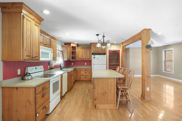 kitchen with white appliances, a breakfast bar, a kitchen island, light countertops, and glass insert cabinets