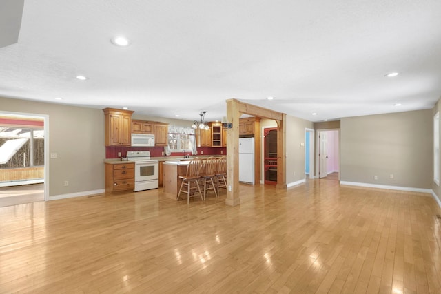 unfurnished living room featuring a healthy amount of sunlight, light wood-style floors, baseboards, and recessed lighting