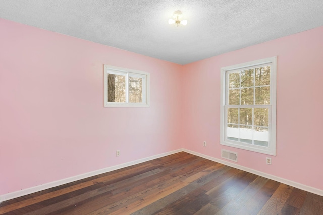 unfurnished room featuring a textured ceiling, dark wood finished floors, visible vents, and baseboards