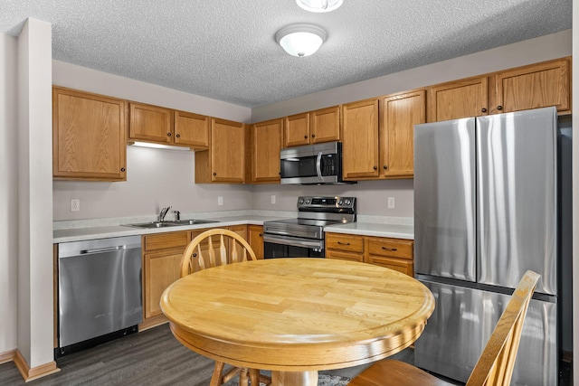 kitchen featuring stainless steel appliances, sink, a textured ceiling, and dark hardwood / wood-style flooring