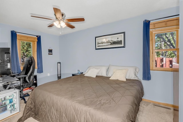 carpeted bedroom featuring multiple windows and ceiling fan