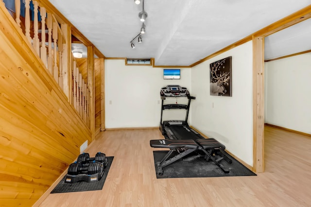 exercise room featuring light hardwood / wood-style flooring, rail lighting, and wooden walls