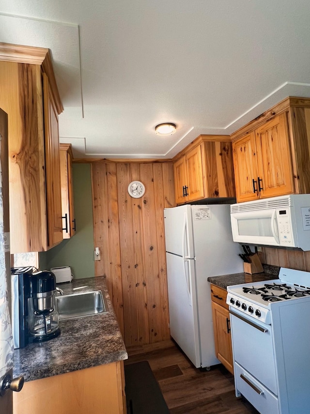 kitchen with sink, white appliances, wooden walls, and dark hardwood / wood-style floors