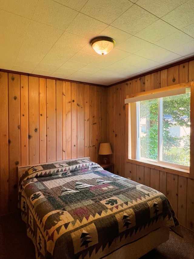 carpeted bedroom with wood walls