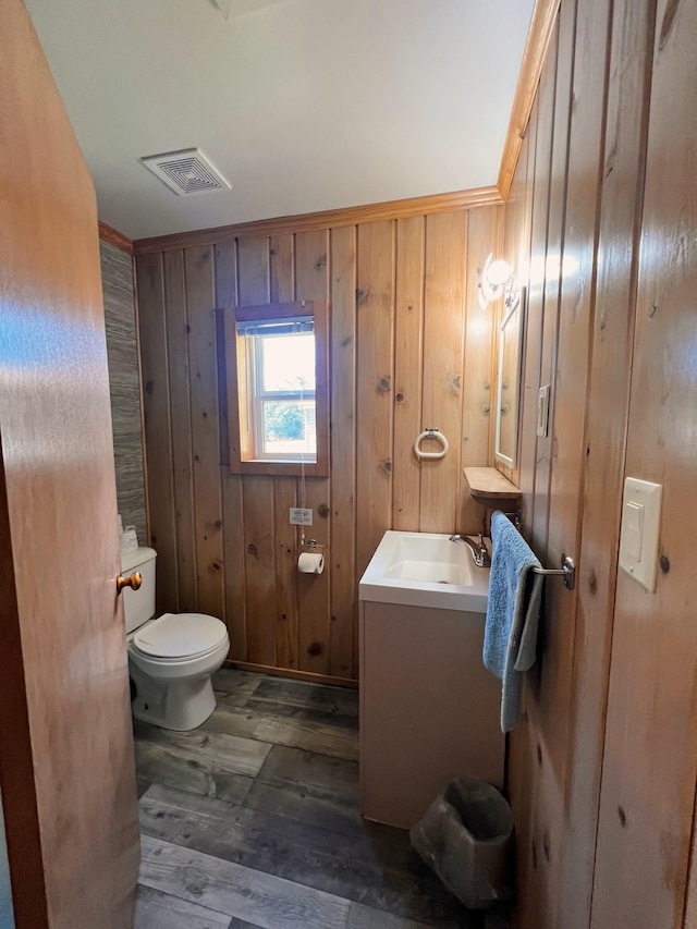 bathroom featuring wood-type flooring, toilet, vanity, and wood walls