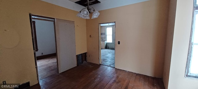 unfurnished dining area with an inviting chandelier and dark hardwood / wood-style flooring