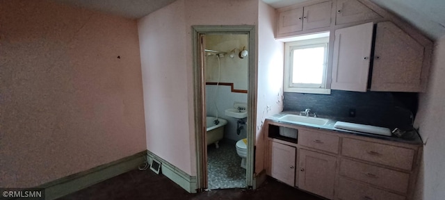 bathroom featuring vanity, a tub to relax in, and toilet