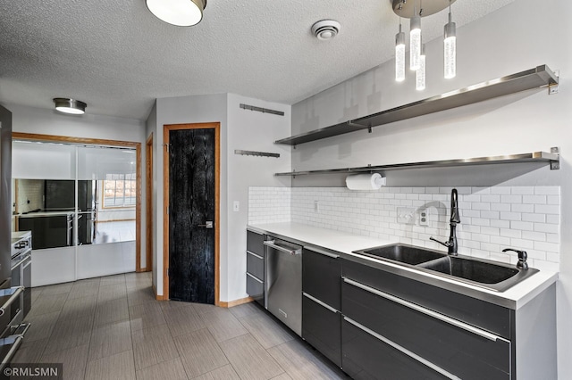 kitchen with sink, tasteful backsplash, a textured ceiling, stainless steel dishwasher, and pendant lighting