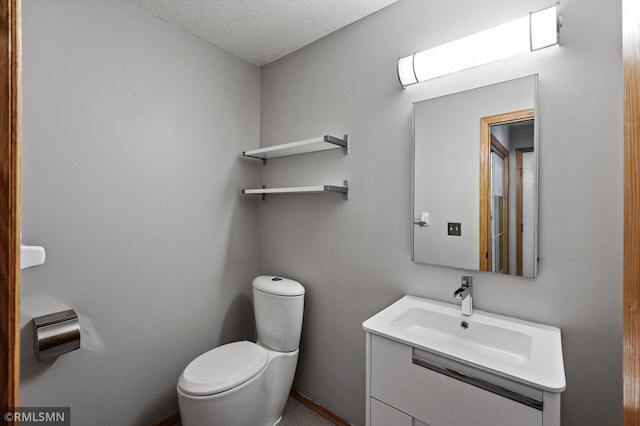 bathroom featuring vanity, toilet, and a textured ceiling