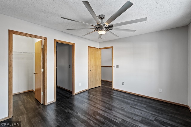 unfurnished bedroom featuring dark hardwood / wood-style floors, a textured ceiling, ceiling fan, and a spacious closet