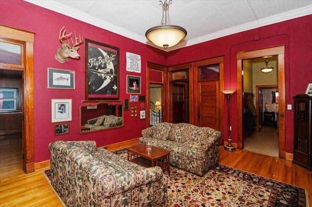 living room with light wood-type flooring, a textured ceiling, and ornamental molding