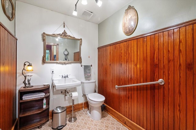 bathroom featuring sink, toilet, wooden walls, and tile patterned flooring