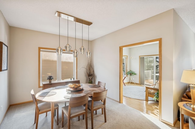 dining area featuring light carpet and a textured ceiling