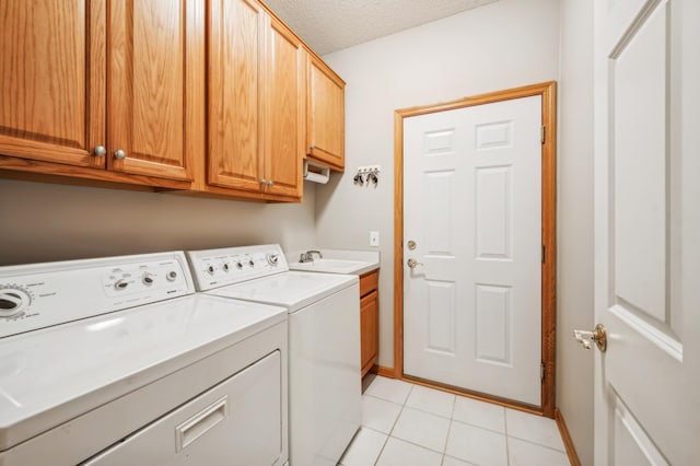 clothes washing area featuring sink, washing machine and dryer, cabinets, a textured ceiling, and light tile patterned flooring