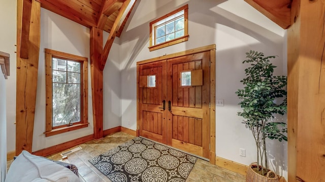 foyer with lofted ceiling with beams, a wealth of natural light, and wood ceiling