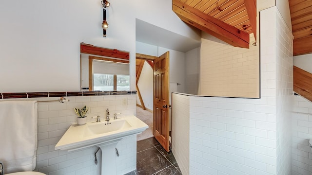 bathroom featuring tile walls and beamed ceiling