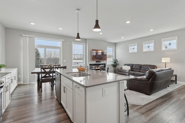 kitchen featuring a center island with sink, sink, appliances with stainless steel finishes, white cabinets, and pendant lighting