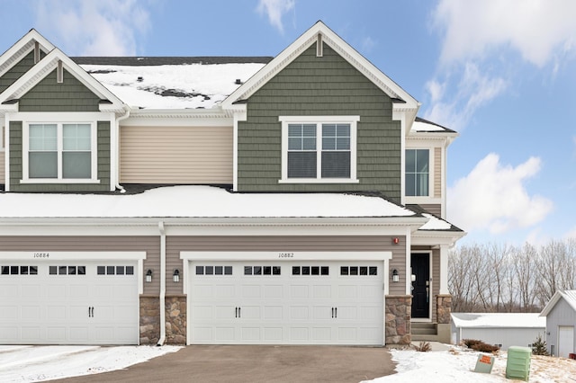 view of front of property with an attached garage, stone siding, and driveway