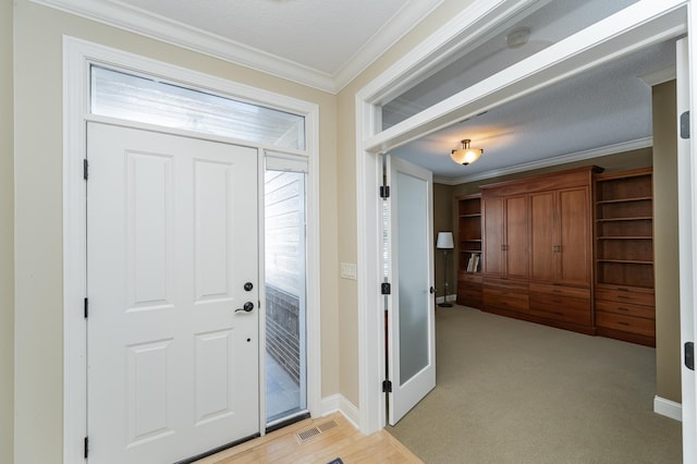 foyer with ornamental molding, light colored carpet, visible vents, and baseboards