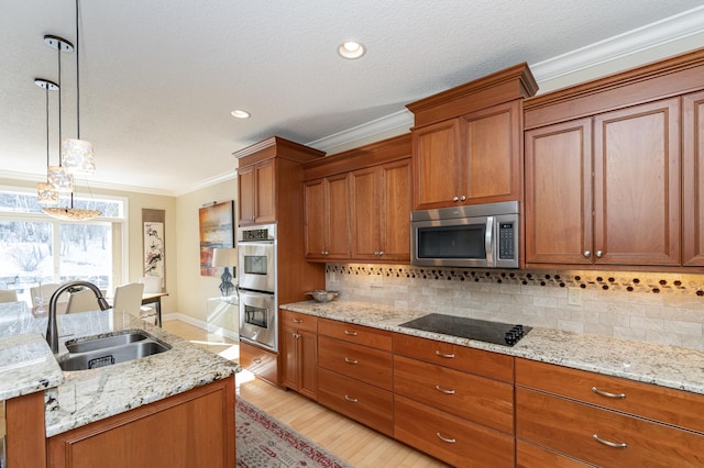 kitchen featuring brown cabinetry, ornamental molding, stainless steel appliances, and a sink