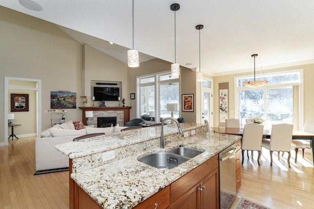 kitchen with brown cabinets, a wealth of natural light, light wood-style floors, open floor plan, and a sink