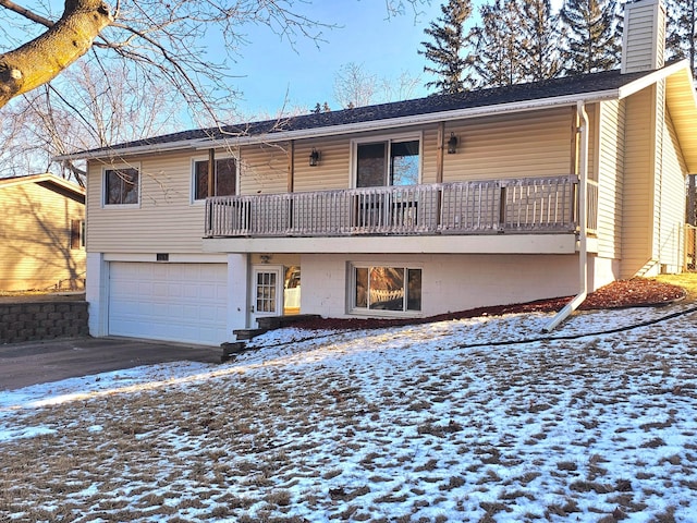 snow covered rear of property with a garage and a balcony