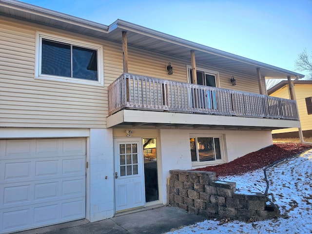 snow covered house featuring a garage and a balcony