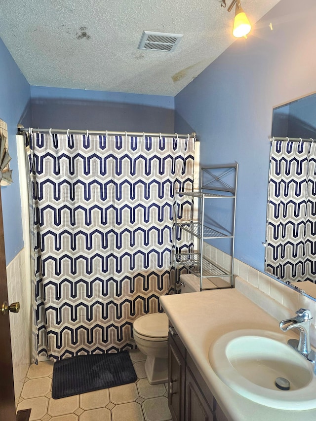 bathroom with vanity, toilet, a shower with shower curtain, and a textured ceiling