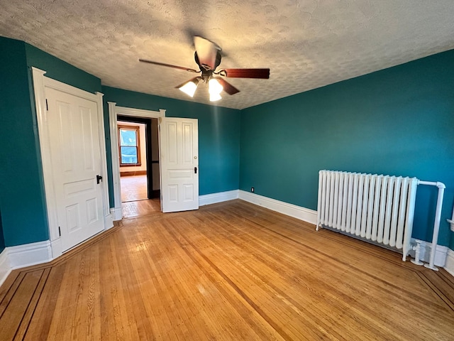 unfurnished bedroom featuring light hardwood / wood-style flooring, a textured ceiling, radiator heating unit, and ceiling fan