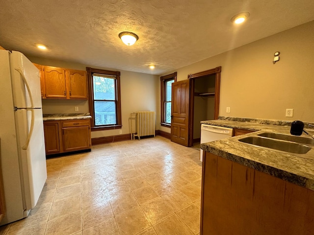 kitchen featuring white appliances, radiator heating unit, sink, and a textured ceiling