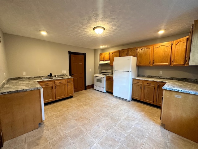 kitchen with sink, white appliances, kitchen peninsula, and a textured ceiling