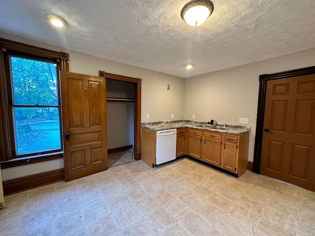 kitchen featuring white dishwasher, light stone countertops, sink, and a textured ceiling