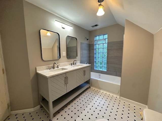 bathroom with vanity, a bath, and vaulted ceiling