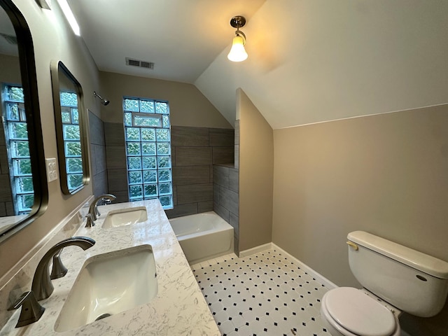 full bathroom featuring toilet, tiled shower / bath, vaulted ceiling, vanity, and tile patterned flooring