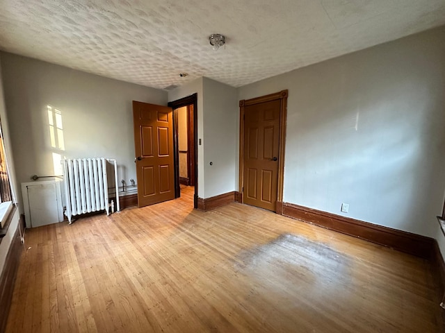 unfurnished bedroom with radiator, a textured ceiling, and light wood-type flooring