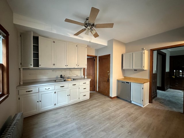 kitchen featuring radiator heating unit, white cabinetry, sink, stainless steel dishwasher, and light hardwood / wood-style floors