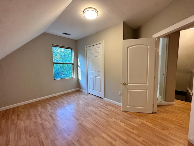 additional living space featuring vaulted ceiling and light hardwood / wood-style flooring