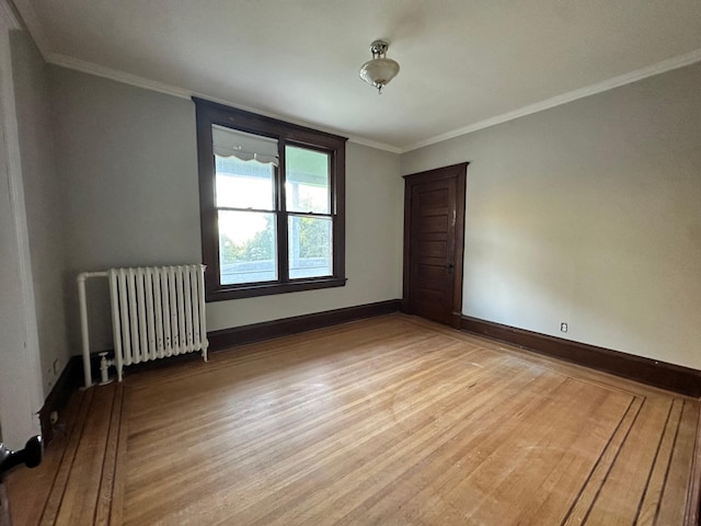 empty room featuring crown molding, radiator heating unit, and light wood-type flooring