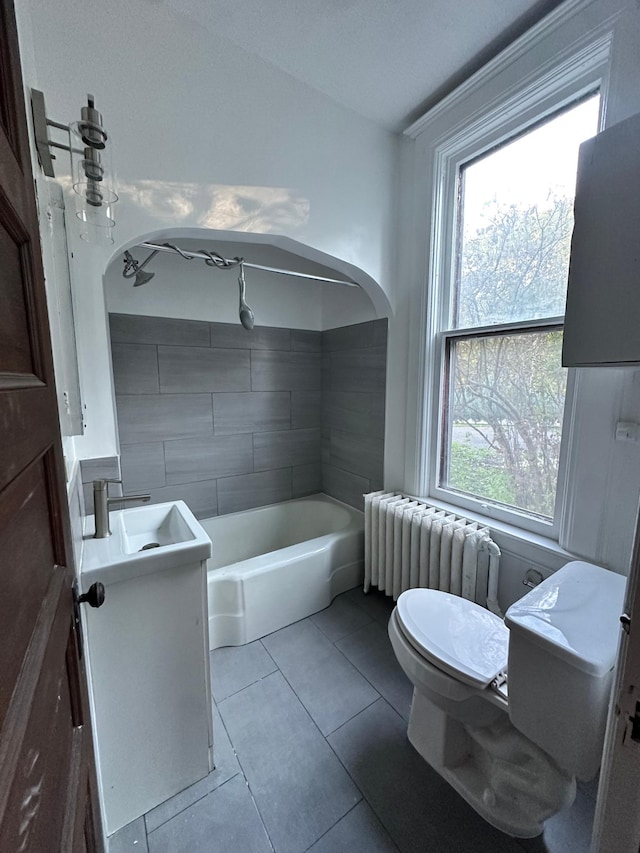 bathroom with a tub to relax in, toilet, tile patterned floors, vanity, and radiator